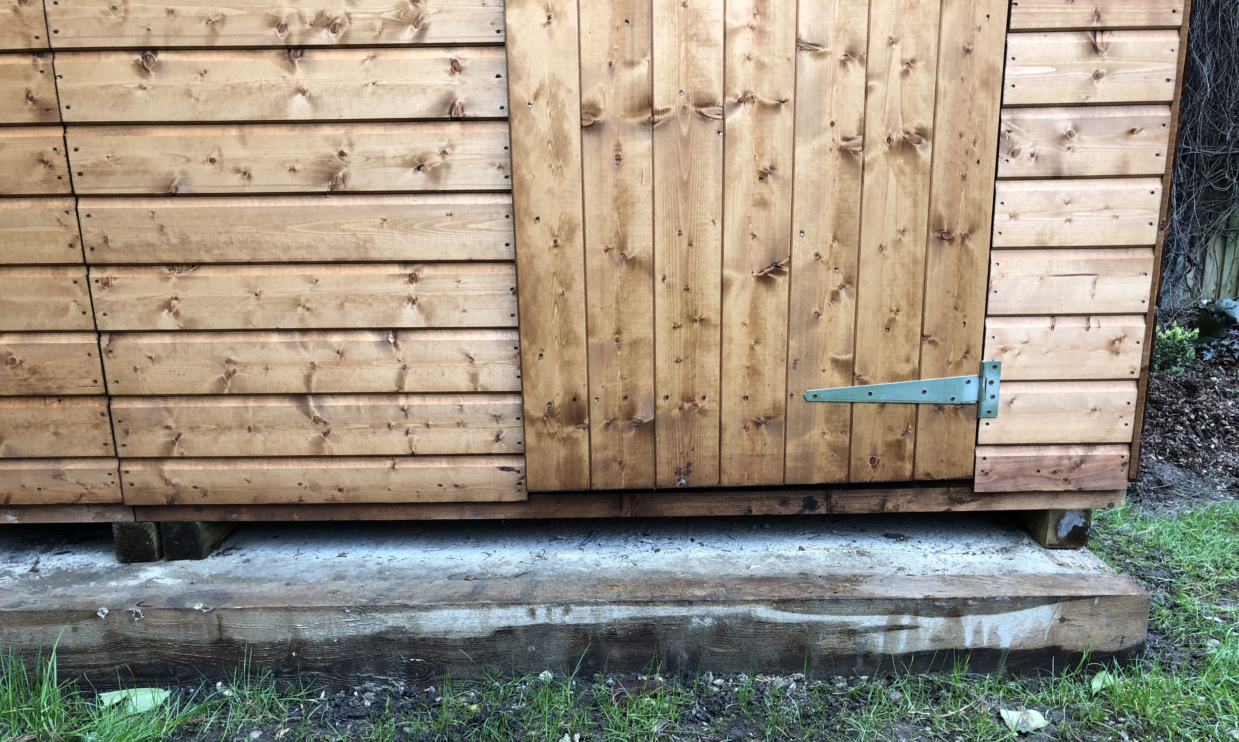 lower front section of a wooden shed on a concrete foundation