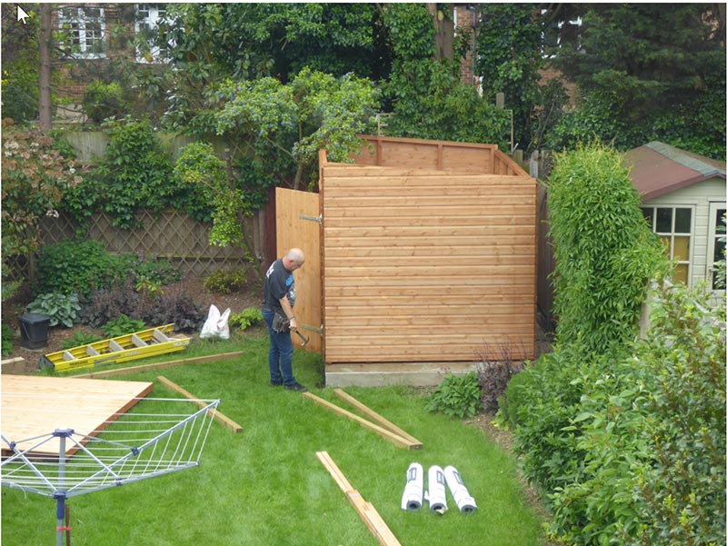 man erecting a wooden garden shed
