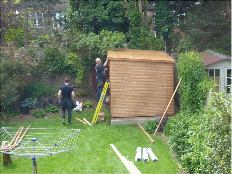 two men constructing a wooden garden shed