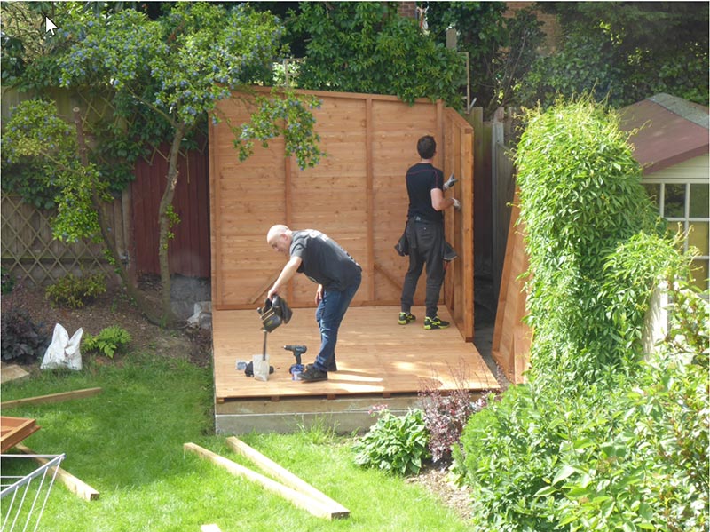 two men erecting a wooden garden shed
